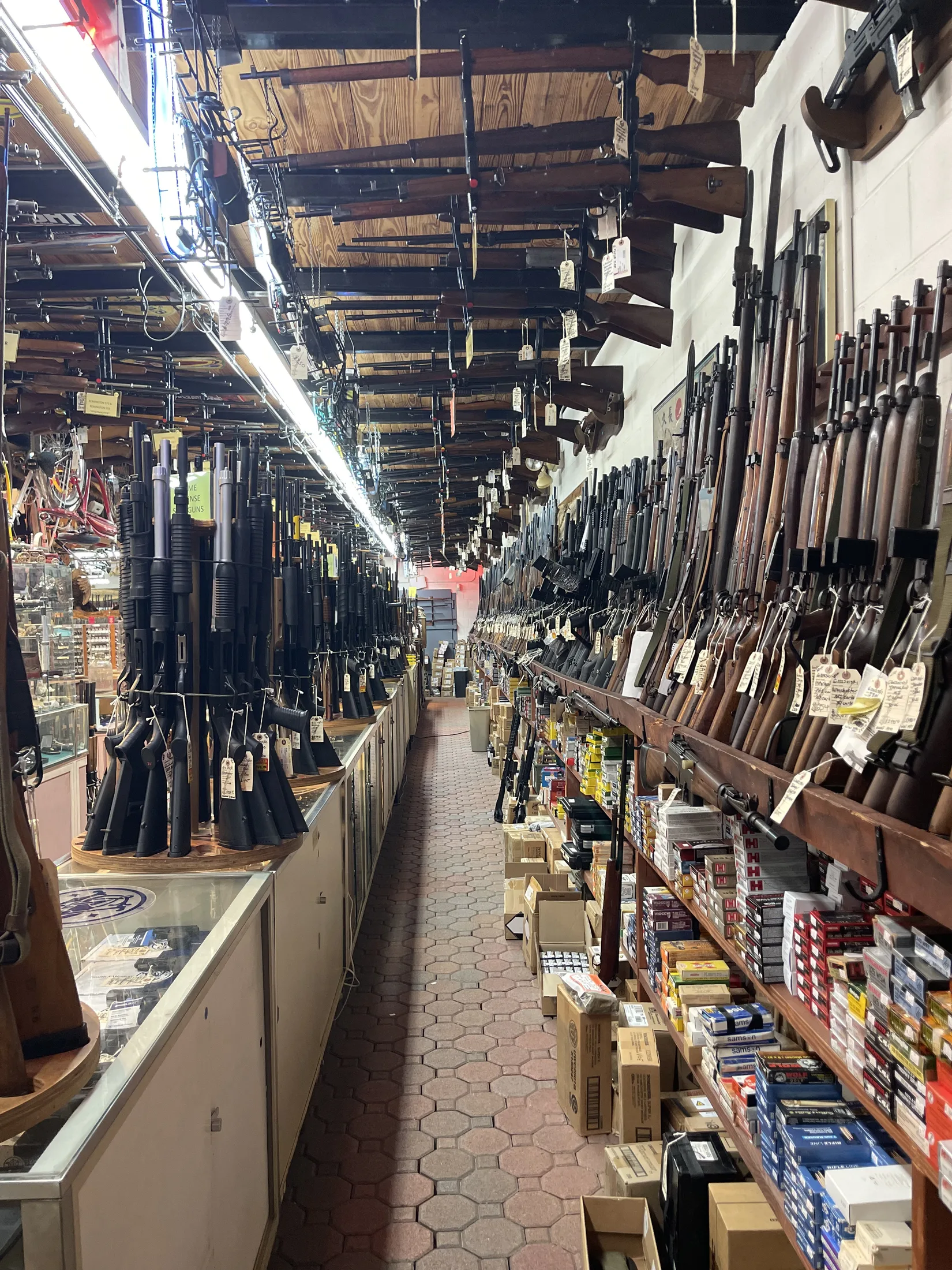 Long aisle of firearms racks and ammunition shelves inside AAA Gun & Pawn