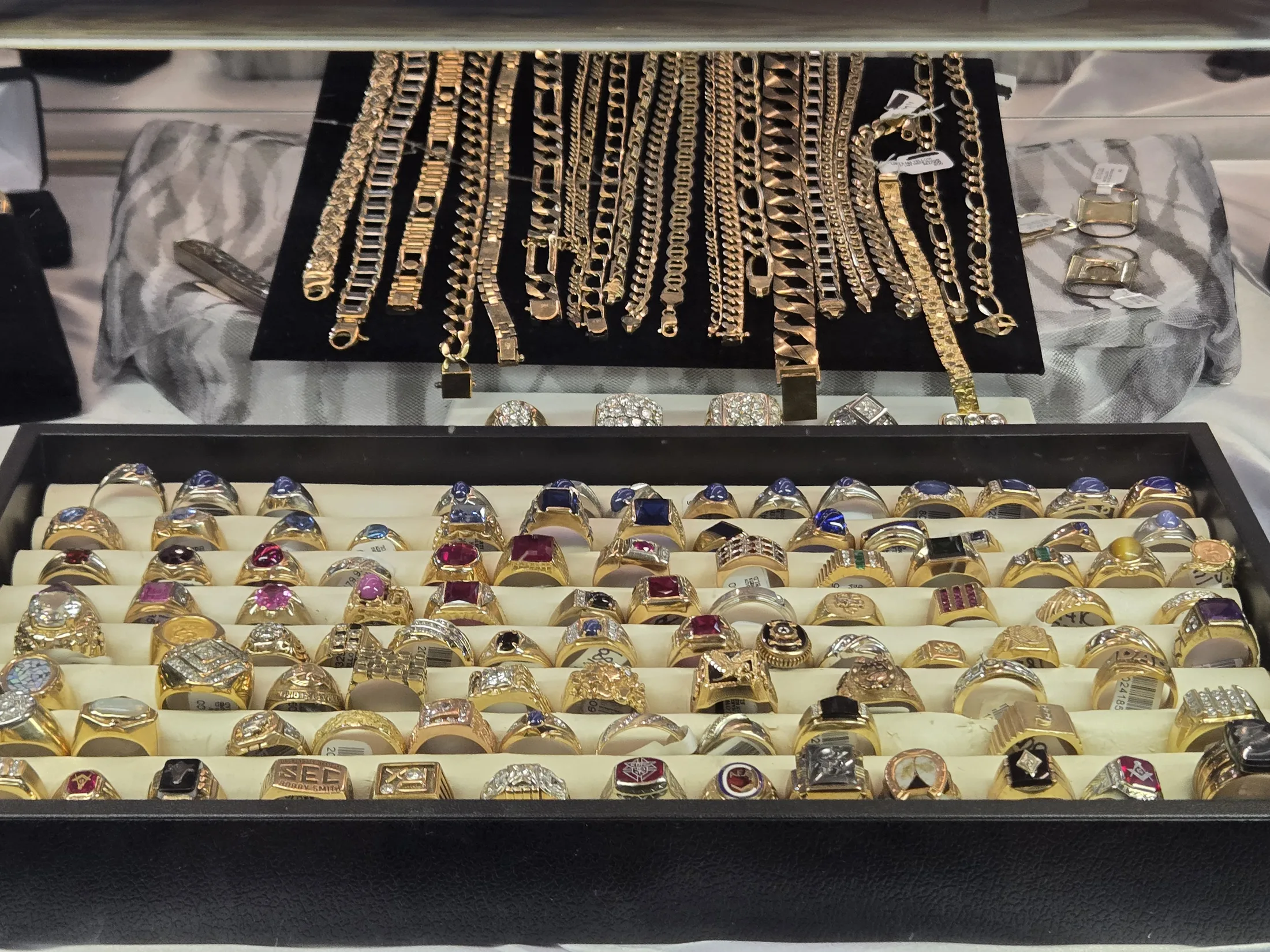 Gold chains and a tray of rings in the jewelry display at AAA Gun & Pawn